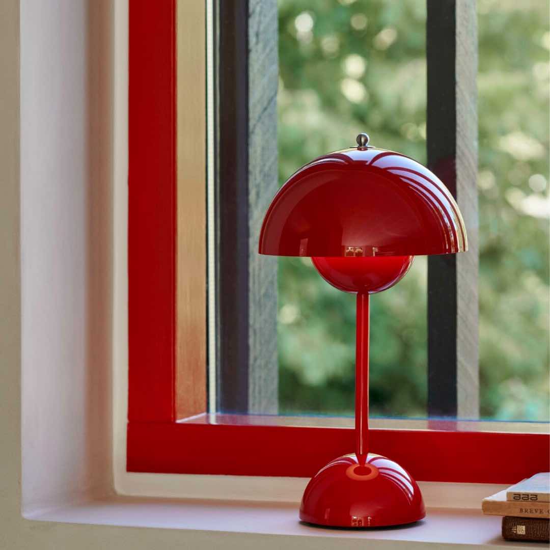 Bild på VP9 bordslampa i röd färg från varumärket &tradition som står på en fönsterbräda.